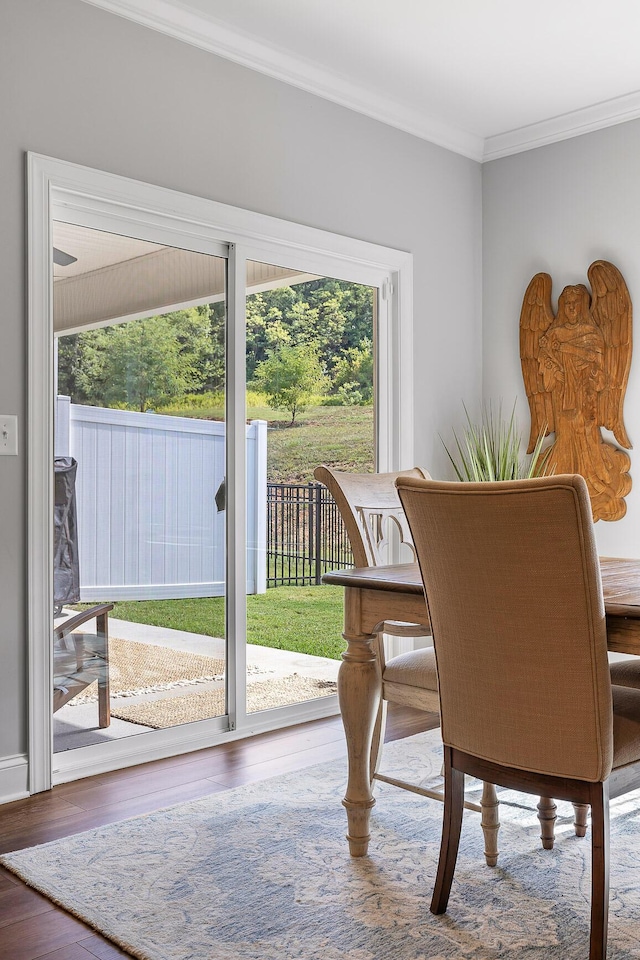 dining space featuring wood-type flooring, ornamental molding, and a healthy amount of sunlight