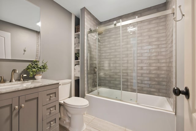 full bathroom with tile patterned floors, bath / shower combo with glass door, toilet, and vanity