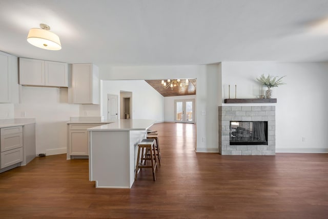 kitchen featuring a kitchen bar, dark wood-type flooring, and white cabinetry