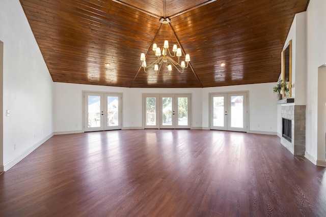 unfurnished living room with high vaulted ceiling, hardwood / wood-style floors, a tile fireplace, and french doors