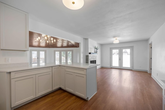 kitchen featuring dark wood-type flooring, kitchen peninsula, french doors, and an inviting chandelier