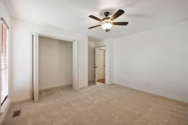 unfurnished bedroom featuring ceiling fan, a closet, and light colored carpet