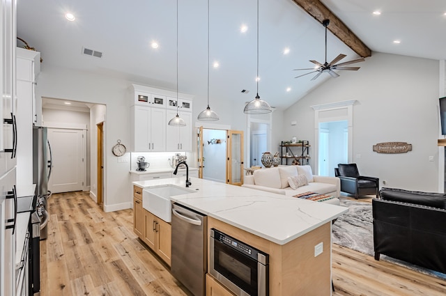 kitchen with stainless steel dishwasher, built in microwave, a center island with sink, light hardwood / wood-style flooring, and white cabinetry