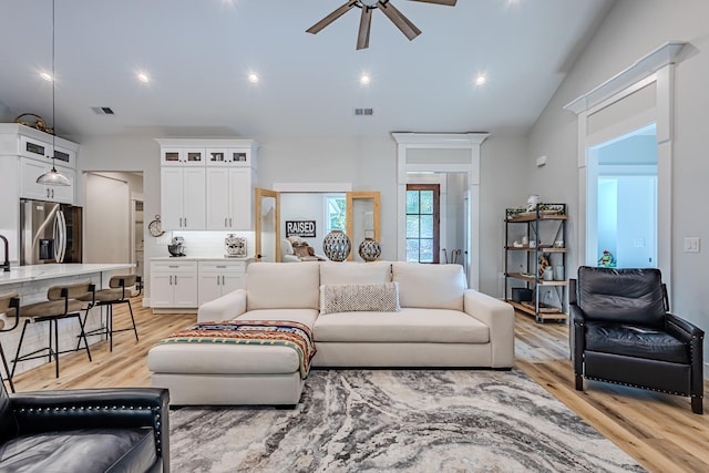 living room with light hardwood / wood-style flooring, ceiling fan, and lofted ceiling