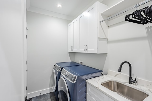 laundry room featuring washing machine and clothes dryer, sink, and cabinets