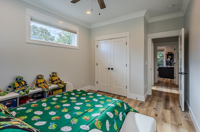 bedroom with light wood-type flooring, a closet, multiple windows, and ceiling fan