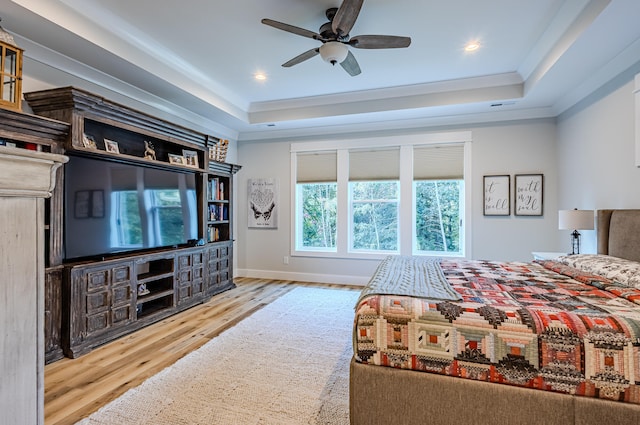 bedroom featuring a tray ceiling, ceiling fan, crown molding, and light hardwood / wood-style floors