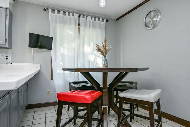 dining space featuring crown molding and light tile patterned flooring