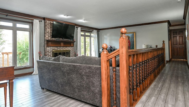 living room with wood-type flooring, a brick fireplace, and crown molding