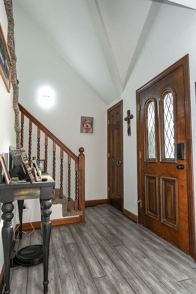 foyer entrance with hardwood / wood-style floors and high vaulted ceiling