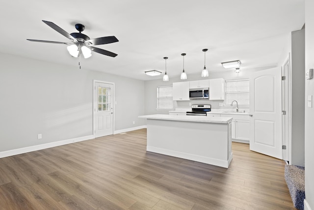 kitchen with stainless steel appliances, sink, pendant lighting, a center island, and white cabinetry