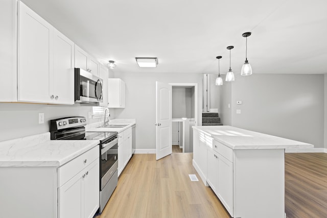 kitchen featuring appliances with stainless steel finishes, sink, pendant lighting, white cabinets, and a center island