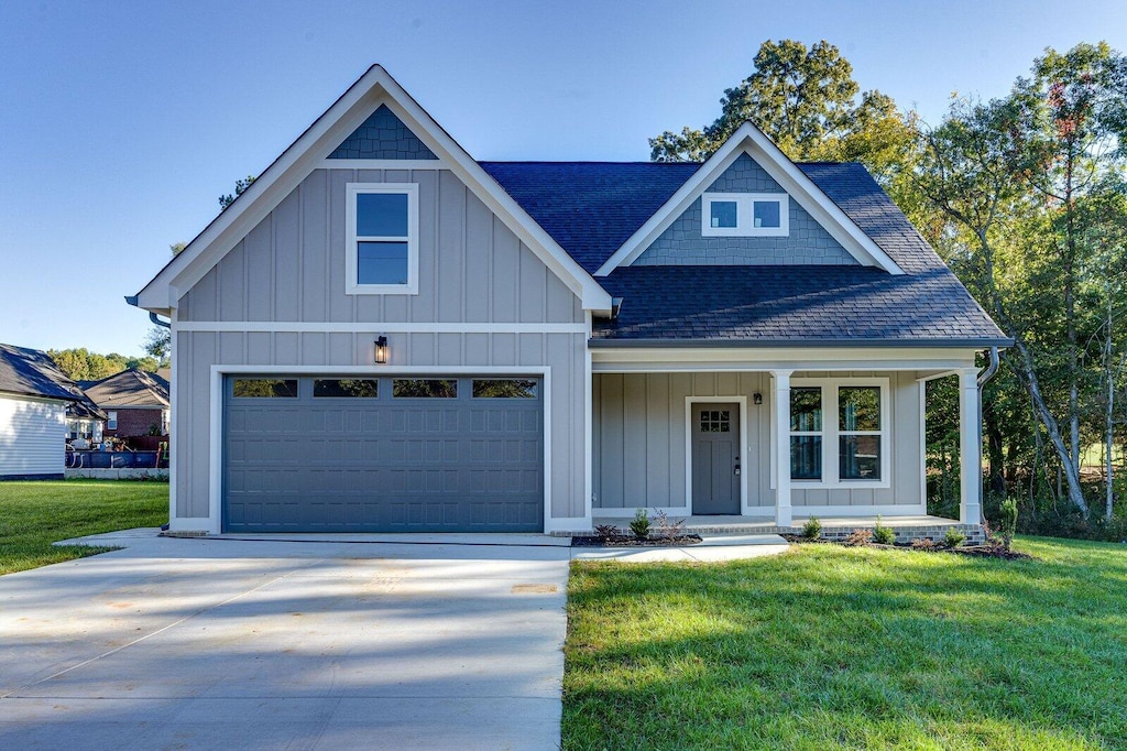 view of front of house featuring a porch, a garage, and a front yard