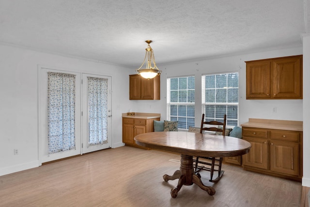 dining space with crown molding, light wood-style floors, baseboards, and a textured ceiling