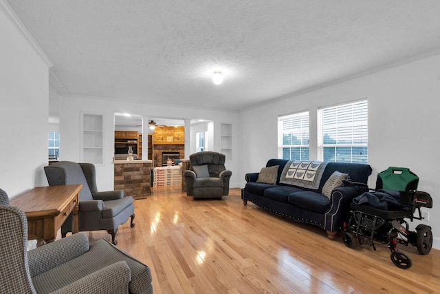 living room with light wood finished floors, built in shelves, and a textured ceiling