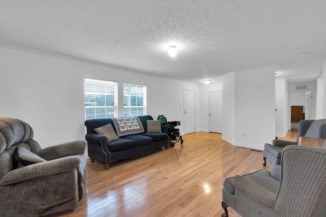 living room with visible vents, crown molding, baseboards, light wood-style floors, and a textured ceiling