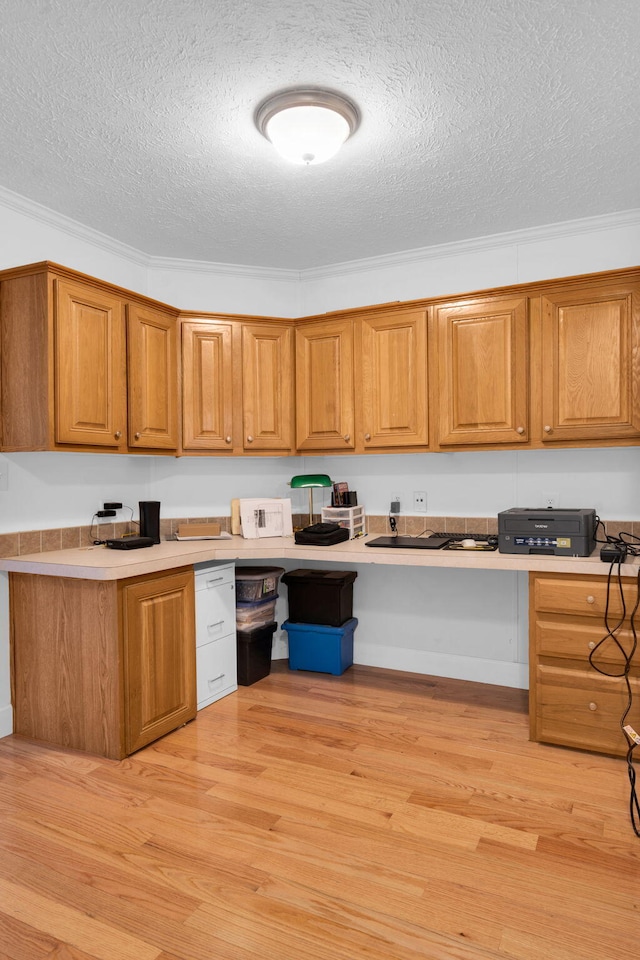 kitchen featuring light countertops, light wood-style floors, brown cabinets, and a textured ceiling