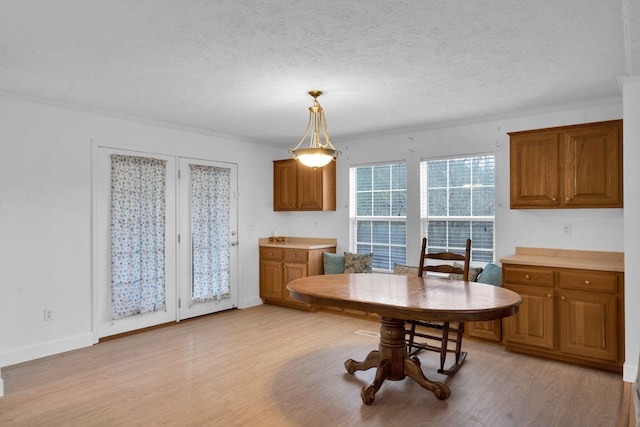 dining room with crown molding, baseboards, light wood-type flooring, and a textured ceiling