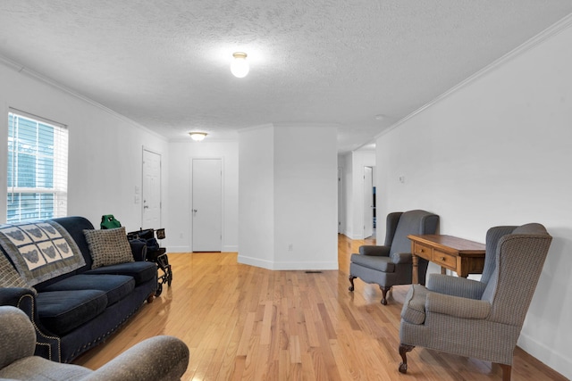 living area featuring light wood-style floors, crown molding, and a textured ceiling