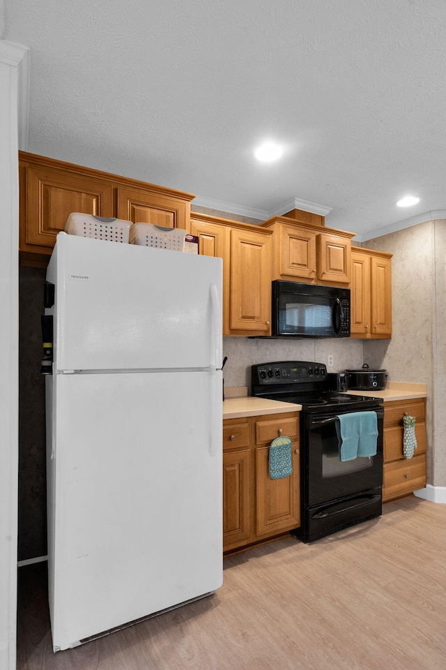 kitchen featuring black appliances, light countertops, light wood-style floors, and ornamental molding