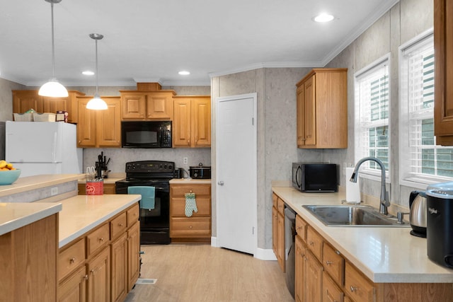 kitchen featuring light countertops, ornamental molding, light wood-style floors, black appliances, and a sink