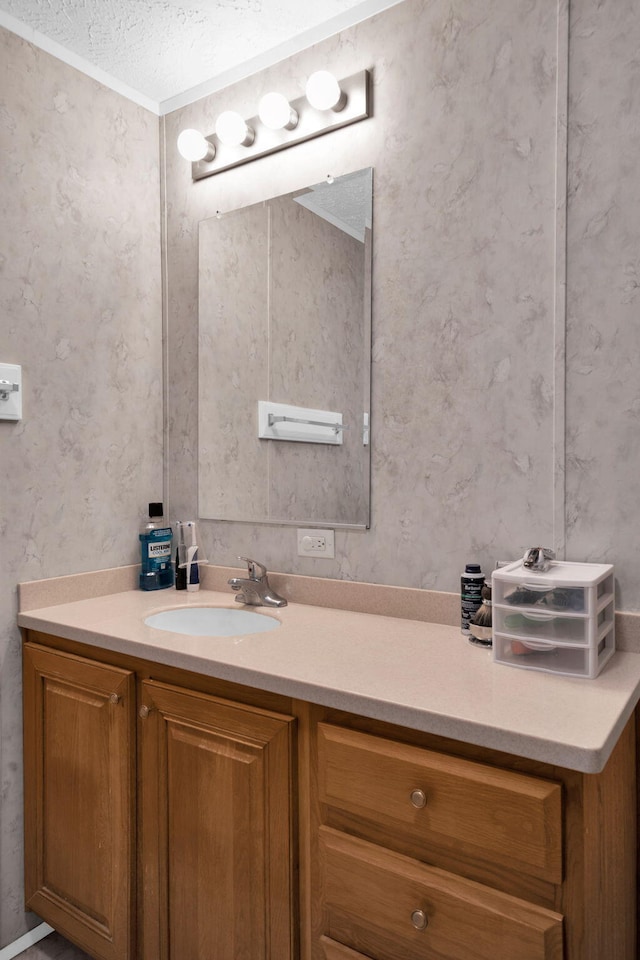 bathroom featuring wallpapered walls, vanity, and a textured ceiling