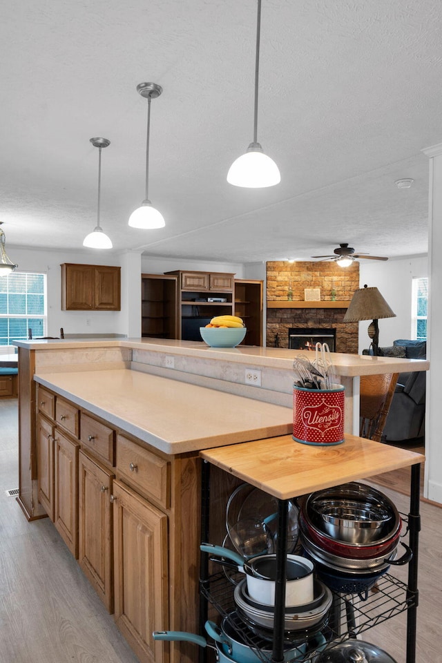 kitchen with light countertops, a fireplace, light wood-type flooring, and a kitchen island