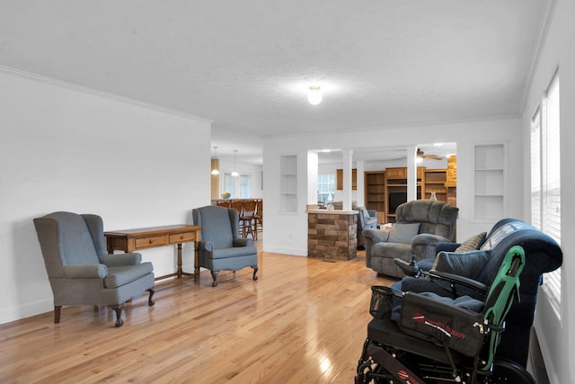 sitting room featuring crown molding, plenty of natural light, and light wood-style floors