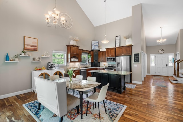 dining room with high vaulted ceiling, a notable chandelier, baseboards, and hardwood / wood-style floors