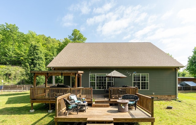 rear view of property featuring a lawn, fence, a wooden deck, and a shingled roof