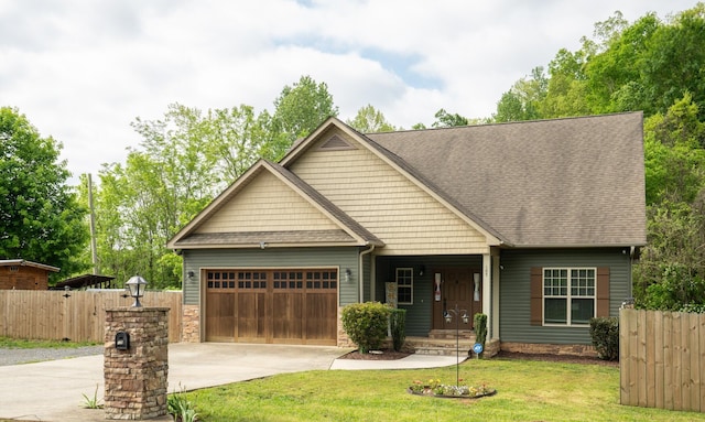 craftsman-style home featuring an attached garage, fence, driveway, and a front yard
