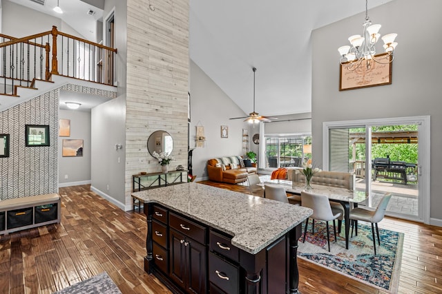 kitchen featuring high vaulted ceiling, an accent wall, decorative light fixtures, baseboards, and dark wood-style floors