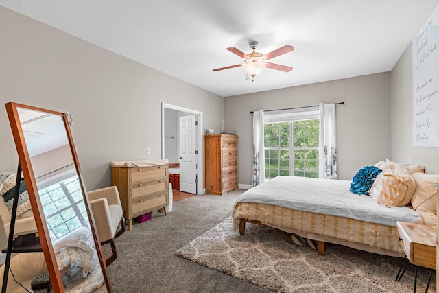 carpeted bedroom featuring ensuite bathroom and a ceiling fan