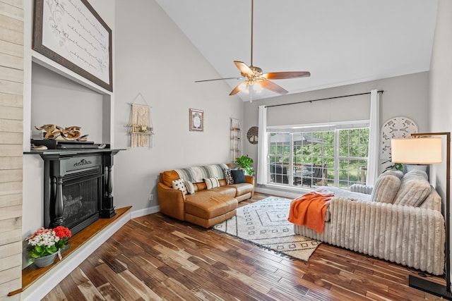 living room with a fireplace with raised hearth, high vaulted ceiling, a ceiling fan, baseboards, and wood finished floors