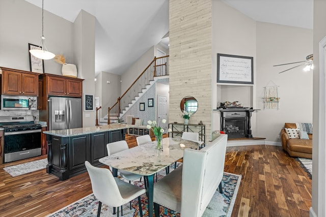 dining area with high vaulted ceiling, a glass covered fireplace, and dark wood-style floors