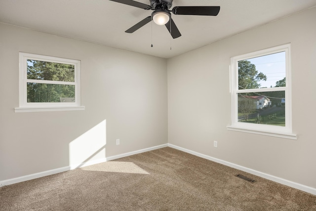 carpeted spare room featuring a wealth of natural light and ceiling fan