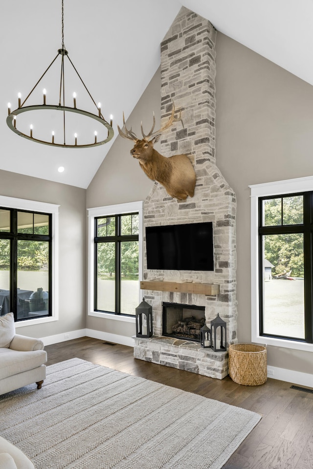 living room with dark hardwood / wood-style floors, a stone fireplace, and high vaulted ceiling