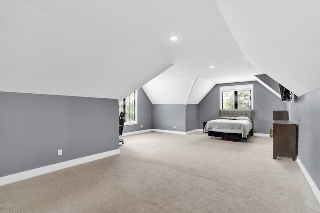 unfurnished bedroom featuring light colored carpet, vaulted ceiling, and multiple windows