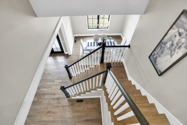 stairs featuring an inviting chandelier and hardwood / wood-style flooring