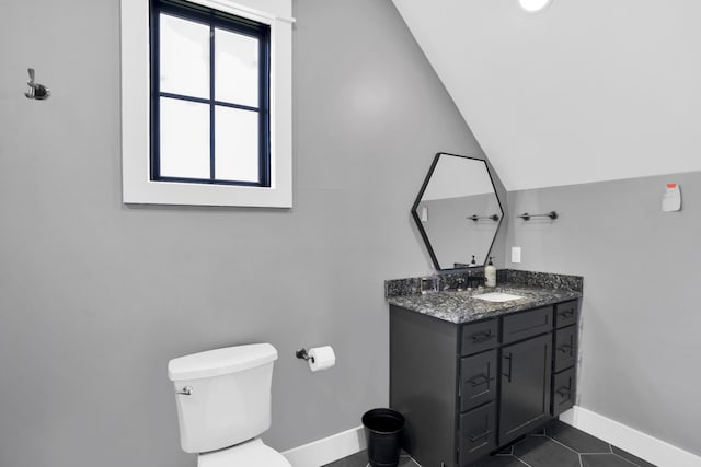 bathroom with tile patterned floors, vanity, lofted ceiling, and toilet