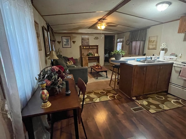 kitchen with vaulted ceiling, white range with electric stovetop, sink, dark hardwood / wood-style flooring, and kitchen peninsula