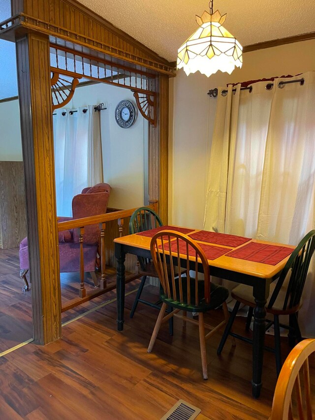 dining area featuring hardwood / wood-style flooring, ornamental molding, vaulted ceiling, and a textured ceiling