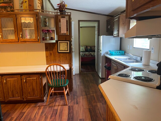 kitchen with dark hardwood / wood-style floors, built in desk, lofted ceiling, sink, and white appliances