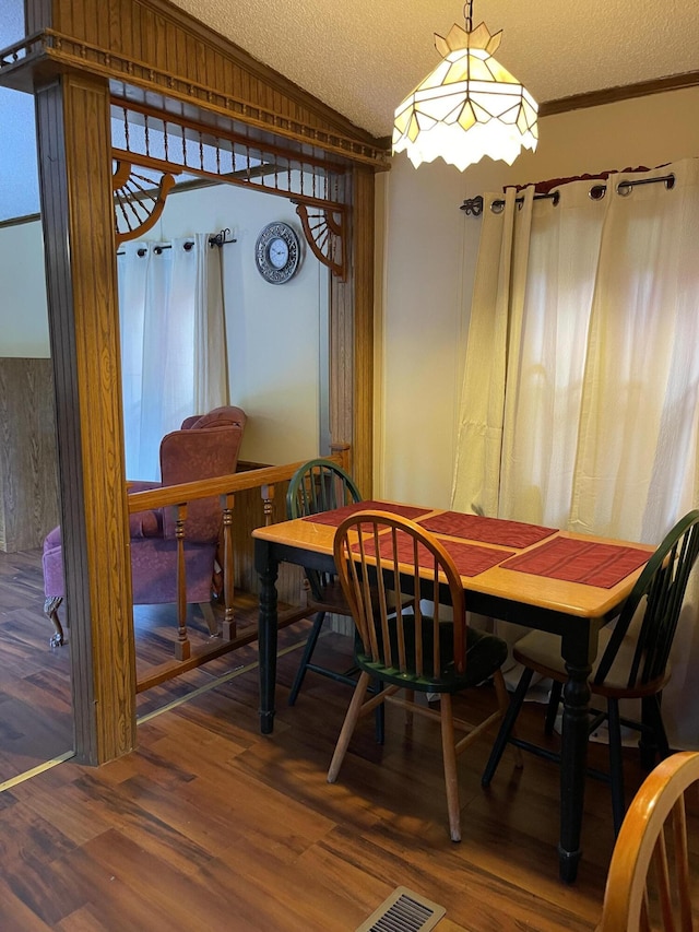 dining room featuring ornamental molding, lofted ceiling, hardwood / wood-style floors, and a textured ceiling