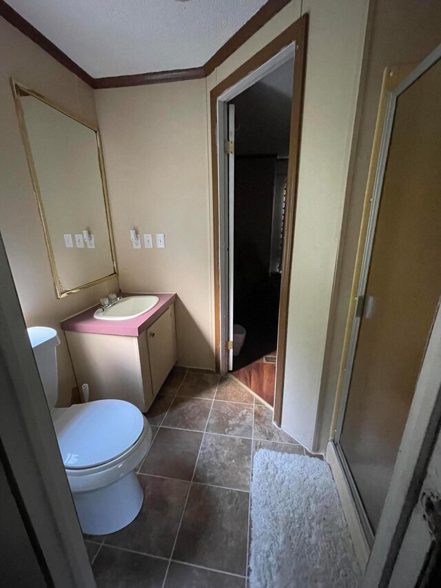 bathroom featuring vanity, ornamental molding, walk in shower, toilet, and a textured ceiling