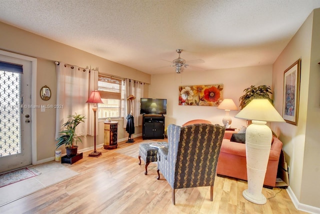 living room featuring a textured ceiling, ceiling fan, and light hardwood / wood-style flooring