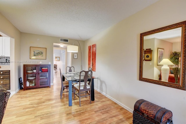 dining space featuring a textured ceiling and light hardwood / wood-style flooring