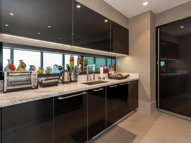 kitchen featuring light stone countertops, sink, and light tile flooring