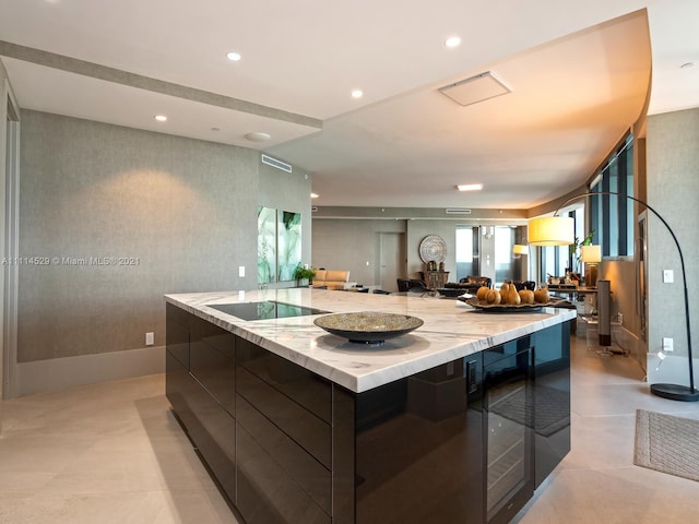 kitchen with light tile floors, a kitchen island, black electric cooktop, light stone countertops, and dark brown cabinetry