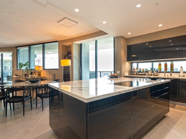 kitchen with light tile flooring, light stone countertops, a center island, and a wealth of natural light